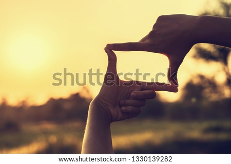 hands making framing view distant over sunset
