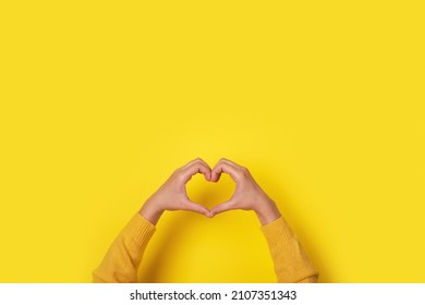 Hands making heart shape, love symbol over yellow background - Shutterstock ID 2107351343