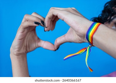 Hands making heart shape with rainbow bracelet on wrist promoting love, diversity, and lgbtq+ rights - Powered by Shutterstock - Get 15% off with code: PIKWIZARD15