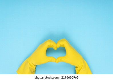 Hands Making Heart Shape With Yellow Cleaning Glove On Blue Background