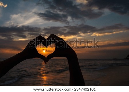 hands making hearts with a beautiful sunset in the background