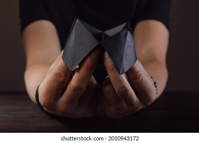 Hands Of Male Fortune Teller With Paper Cootie Catcher On Dark Background