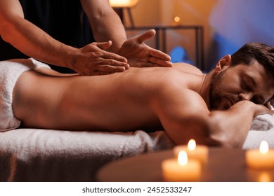 The hands of the male masseur are actively rubbing the visitors back, a therapeutic massage for tired muscles. Point massage in the spa center. Body therapy for a healthy lifestyle. - Powered by Shutterstock