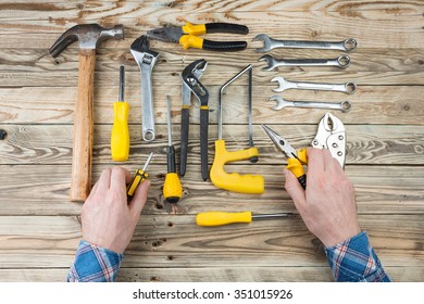 Hands of man in blue plaid shirt holding tools for repair and assembly. Home repair services, calling a master home. Top view