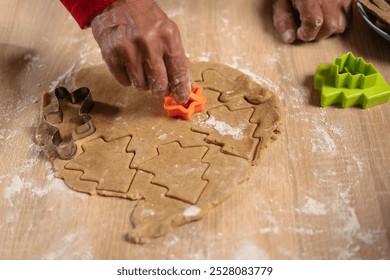 Hands of a man carefully pressing a cookie cutter into gingerbread dough on a wooden table, surrounded by flour and festive ingredients. Capturing Christmas traditions and homemade baking joy - Powered by Shutterstock