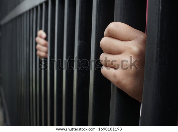 Hands of man catch in the iron\
prison. Man in prison, hope to be free. Crime - Prison Cell\
Bars.
