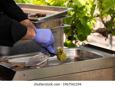 Hands Of A Man With Gloves Putting A Falafel Mix Into A Frying Container