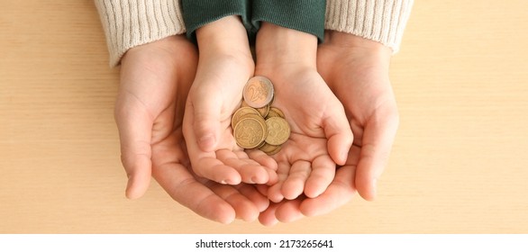 Hands of man and his son holding coins on wooden background. Concept of alimony - Shutterstock ID 2173265641