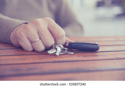 Hands of man holding the car keys on wooden table