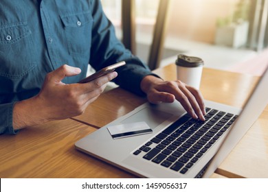 Hands of man are holding smart phones and using laptops computers are entering websites to buy products.