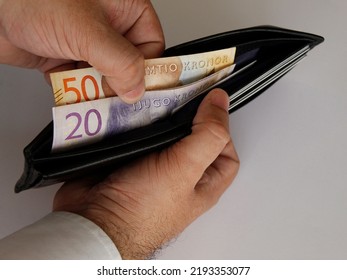 Hands Of A Man Holding Swedish Bills And A Black Leather Wallet