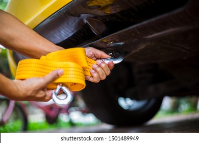 Hands of man holding yellow car towing strap with yellow car. Yellow car towing. towing rope.
