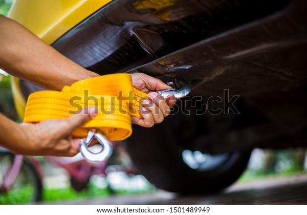Hands of man holding yellow car\
towing strap with yellow car. Yellow car towing. towing\
rope.