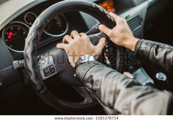 The hands of a man on the steering wheel pressing\
the siren