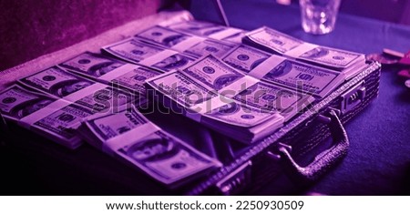 Hands of a man placing stacks of US dollars into a black briefcase. Preparing for a poker game and the money is his bankroll. The money is neatly arranged and organized in the briefcase.