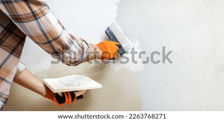 Hands man plasterer construction worker at work with trowel, plastering a wall. Do it yourself concept. Home renovation.