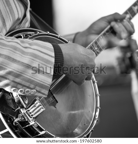 Hands of the man playing the banjo in black and white