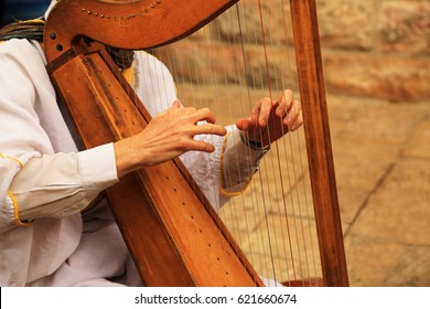 Hands Of A Man Playing On An Old Harp