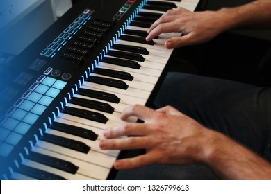 Hands Of A Man Playing Synth Keys With Blue Backlight