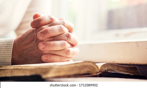 Hands of a man praying over a Bible - represents faith and spirituality in everyday life