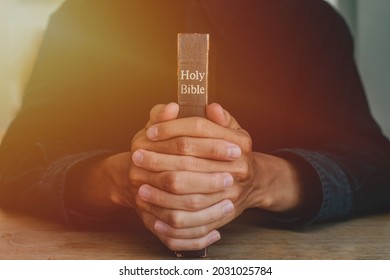 Hands Of A Man Praying Over A Bible Represents Faith And Spirituality In Everyday Life. Close Up. 