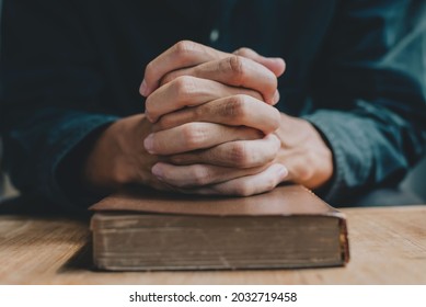 Hands Of A Man Praying Over A Bible Represents Faith And Spirituality In Everyday Life. Close Up. 