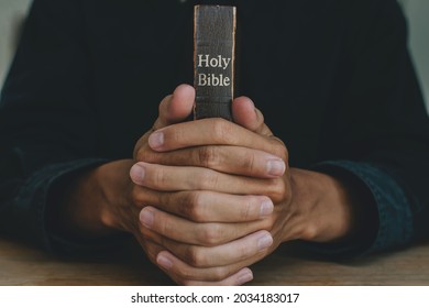 Hands Of A Man Praying Over A Bible Represents Faith And Spirituality In Everyday Life. Close Up. 