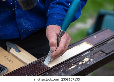 Hands of a man processing wooden elements with a chisel. Professional hand craft work and do it yourself