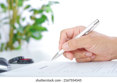 In the hands of a man signing a contract written in Japanese