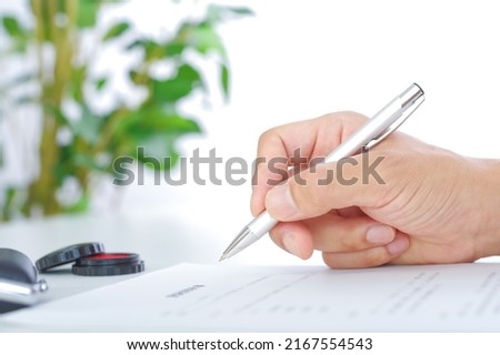 In the hands of a man signing a contract written in Japanese