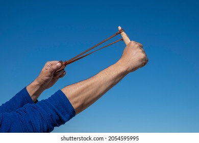 Hands Of A Man Stretching The Elastic Band Of A Slingshot.