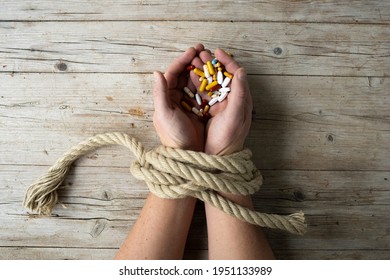 Die Hände des Menschen sind mit einem Seil verbunden und in seinen Händen hält er viele verschiedene Pillen, Concept Sucht, Drogensucht, Foto von oben aufgenommen