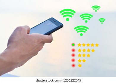 Hands Of A Man Is Using The Black Smartphone With Green Wifi And Golden Stars Rate Icon And The Green Button On The Five Stars Which Means The Signal Is Excellent.Concept For Internet,wifi Speed Test.