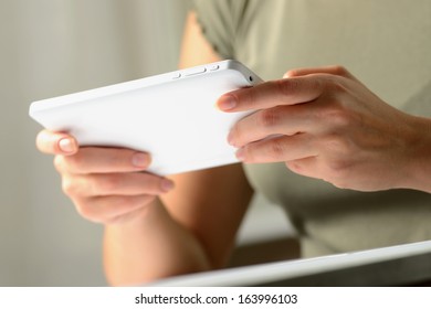 Hands of a man using a white slim PC tablet with high technology, close-up shot from low angle