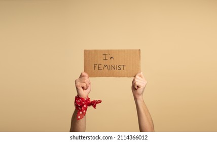 Hands Of A Man, Wearing A Red Bandana With White Polka Dots On His Wrist, Holding A Sign That Reads 