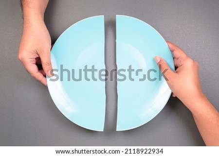 Hands of a man and a woman breaking the dish and split it as two halves, fracture problem in relationships that hard to conciliate