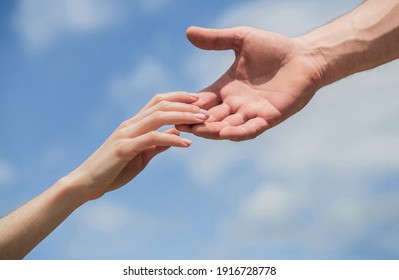 Hands Of Man And Woman Reaching To Each Other, Support. Solidarity, Compassion, And Charity, Rescue. Giving A Helping Hand. Hands Of Man And Woman On Blue Sky Background. Lending A Helping Hand.