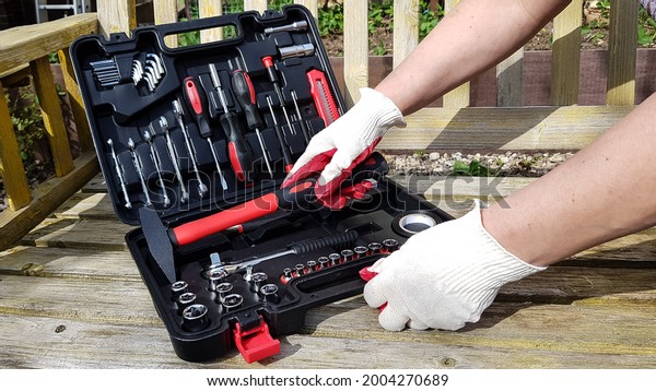 the hands of a man in work gloves open a suitcase\
with various tools. to work, you will need a screwdriver, keys, a\
tape measure, a hammer