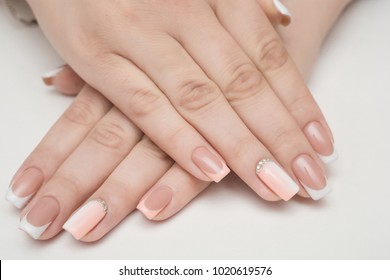 Hands and manicured nails covered and pink nail polish fur background