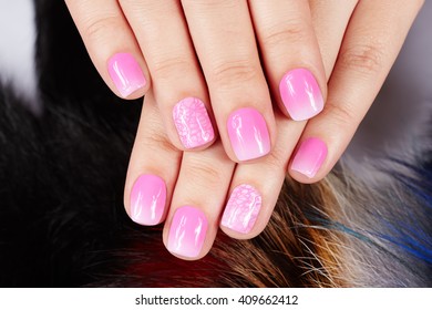 Hands and manicured nails covered and pink nail polish fur background