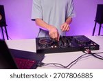 Hands manipulating digital DJ controller deck, green stage lighting, tactile jog wheel, precision mixing, energetic performance vibe, content creator or club DJ