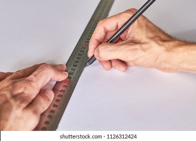 Hands marking a white board, ruller and pencil on a green mat