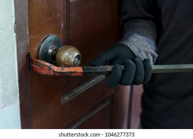 Hands of Masked thief with balaclava using crowbar to breaking into a house at night time. Crime concept.