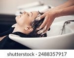 Hands, massage and hairdresser with client in spa, relax and basin for wash and treatment. Soap, salon and hairstyle or cleaning for happy customer person, keratin or scalp shampoo for hair care