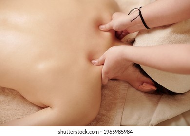 Hands of masseuse massaging myofascial trigger points on back of female client to release tension