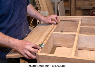 hands of a master carpenter set the hinges on the cabinet. Production of handmade wooden furniture. Selective focus close-up