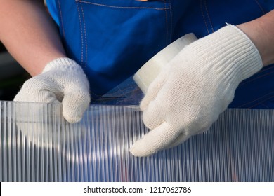 hands of master in gloves glue tape on polycarbonate, close-up