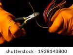 Hands of the master in gloves hold wire cutters and wire closeup on black background. Electronics Repair Idea