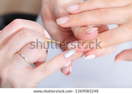 The hands of the master of the hardware manicure and the hands of the client close-up during the application of varn