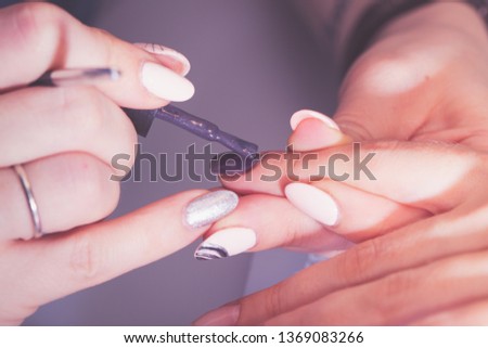 The hands of the master of the hardware manicure and the hands of the client close-up during the application of varn